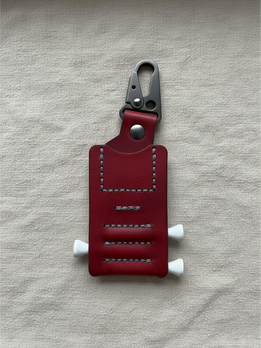 Hidden House Co. deep red leather golf tee caddy with hand-stitched detailing and a heavy-duty carabiner clip.