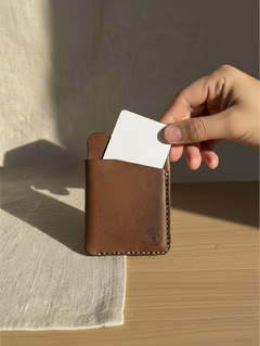 Hidden House Co. brown full-grain leather card holder wallet being held with a white card inserted