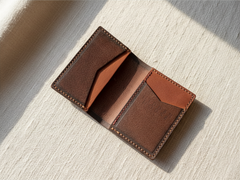 Hidden House Co. handcrafted brown leather bifold card wallet with saddle stitching and minimalist interior slots.