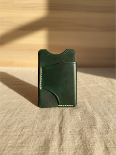 Hidden House Co. forest green leather card holder with hand-stitched details on a textured linen surface.