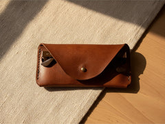 Hidden House Co. handcrafted brown leather glasses case with a brass stud closure and envelope-style design.
