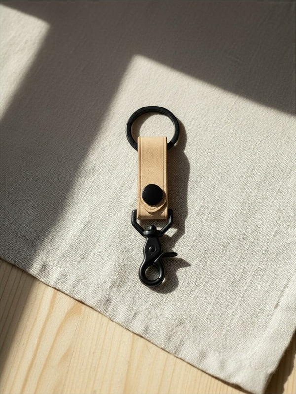 Hidden House Co. minimalist light tan vegetable-tanned leather keychain with matte black metal hardware and snap button.