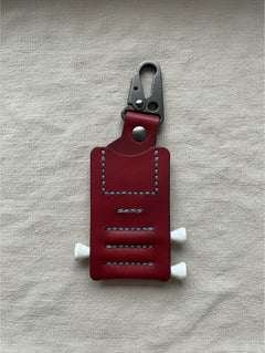 Hidden House Co. deep red leather golf tee caddy with hand-stitched detailing and a heavy-duty carabiner clip.